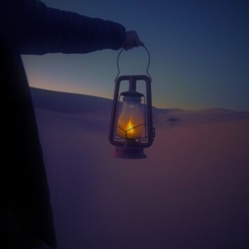 Image of a person holding a lantern in the desert symbolic of undergoing a spiritual journey of inner soul work and ensoulment