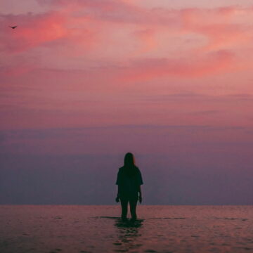 Image of a person standing in the ocean watching the evening sky symbolic of dbt coping skills