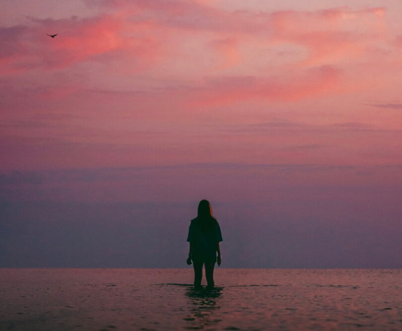 Image of a person standing in the ocean watching the evening sky symbolic of dbt coping skills
