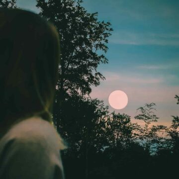 Image of a woman staring at the moon at dusk symbolic of feeling lost on the soul's path