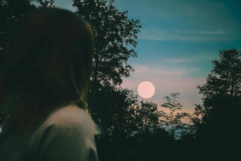 Image of a woman staring at the moon at dusk symbolic of feeling lost on the soul's path