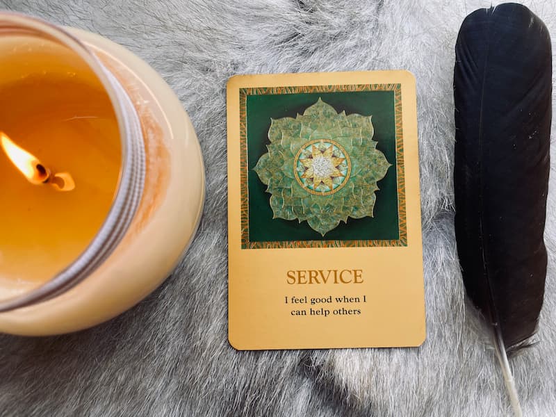 Image of an oracle card that says "Service" next to a feather and candle