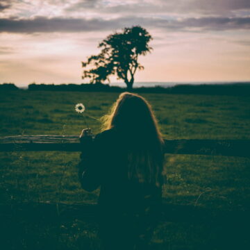 Image of someone spending time alone in front of a green pasture
