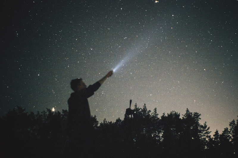 Image of a man shining a torch into the universe