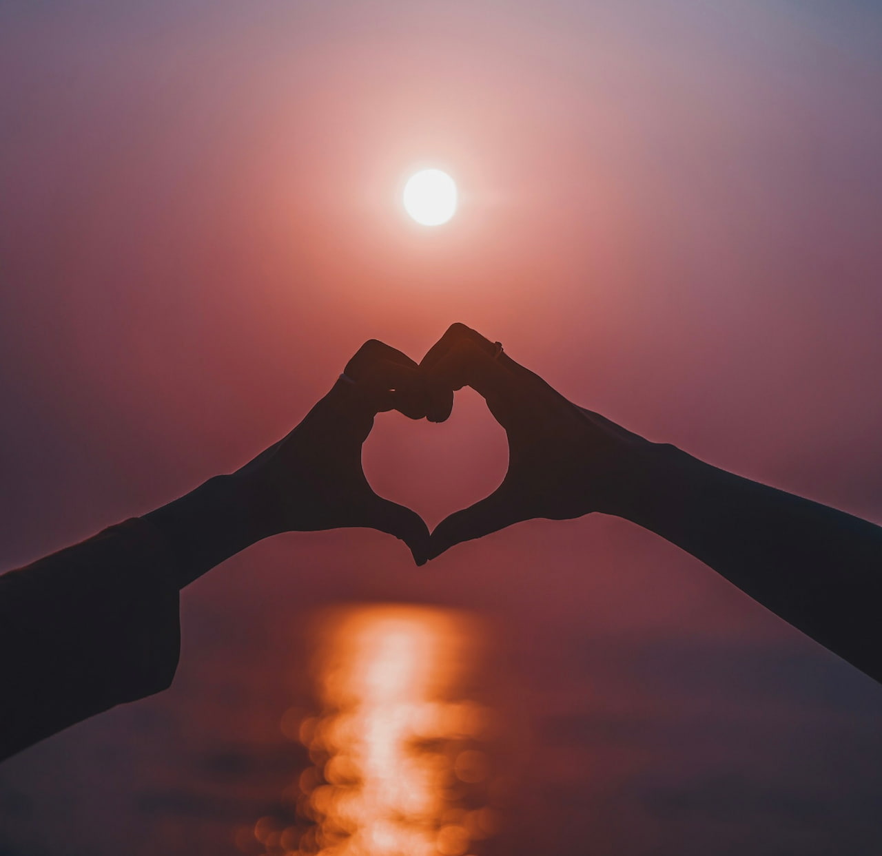 Image of two people putting their hands together to form a love heart symbolic of soul connections