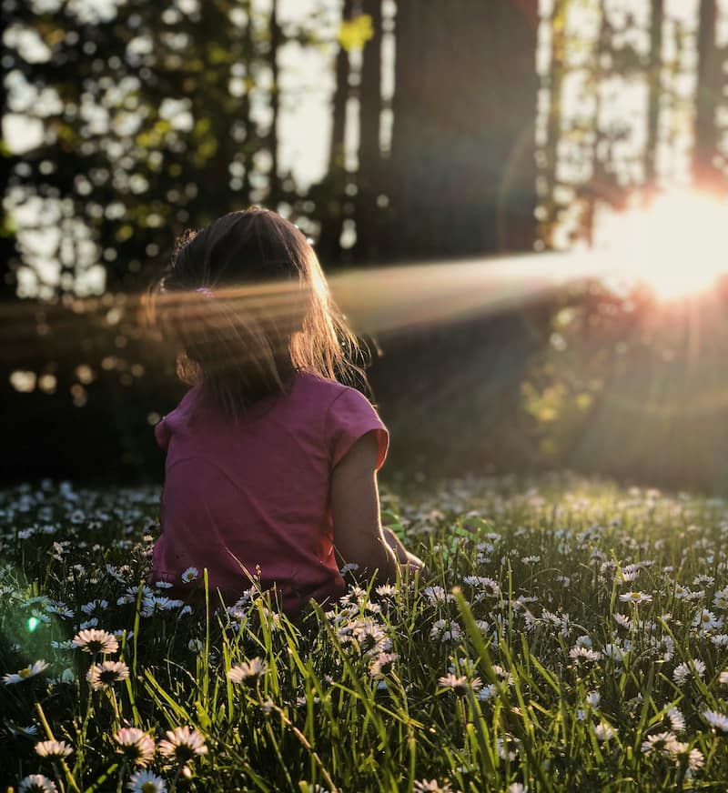 Image of a little girl looking up into the trees symbolic of learning how to mother yourself