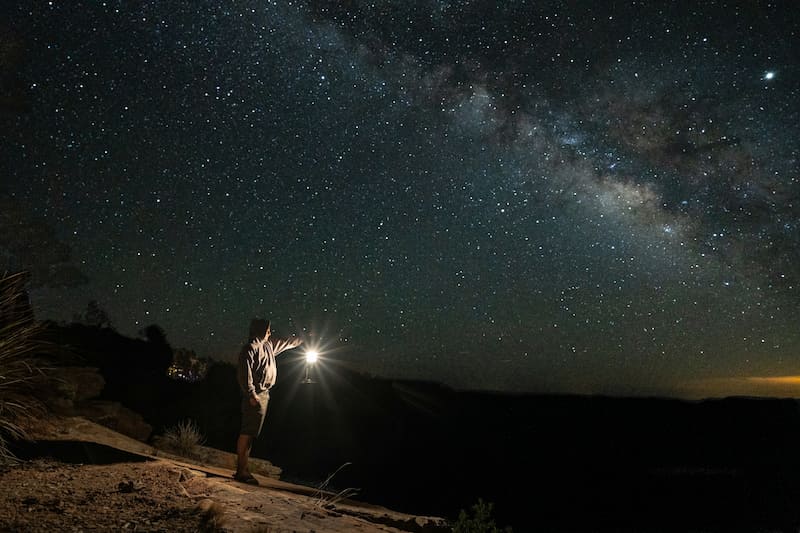 an image of a man holding a lantern under the stars, symbolizing the journey of a self-taught coach
