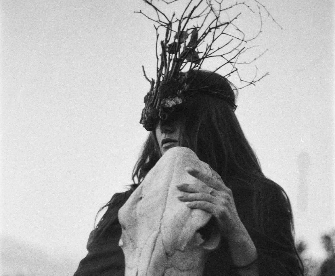 image of a highly sensitive empathic woman wearing a headdress of sticks and holding a skull symbolic of shadow work